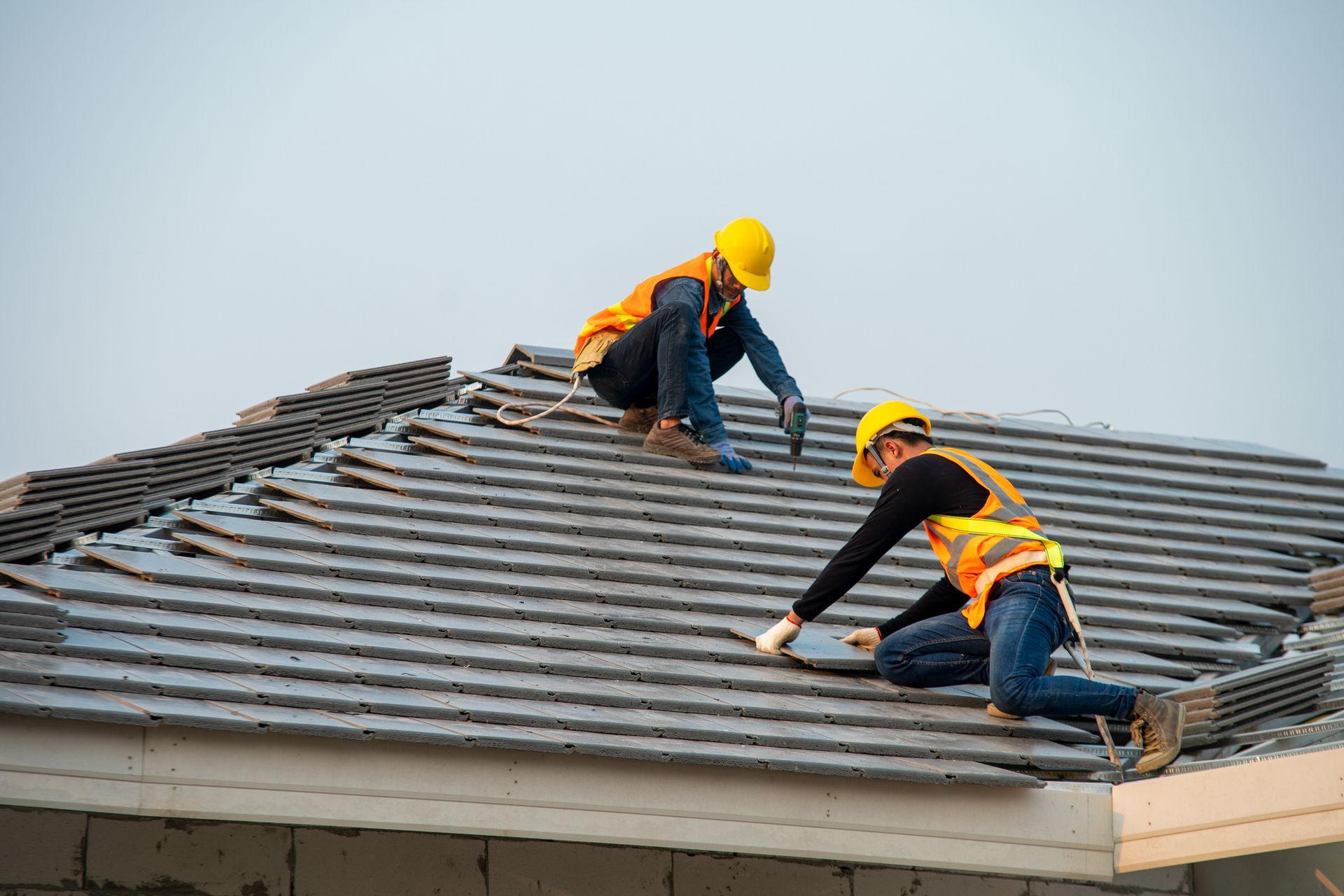 Workers installing roof tiles on a house during professional residential roofing services.
