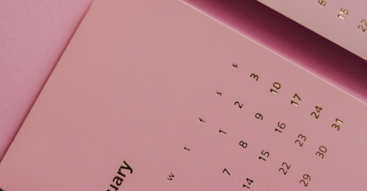 A close up of a pink calendar on a pink surface.