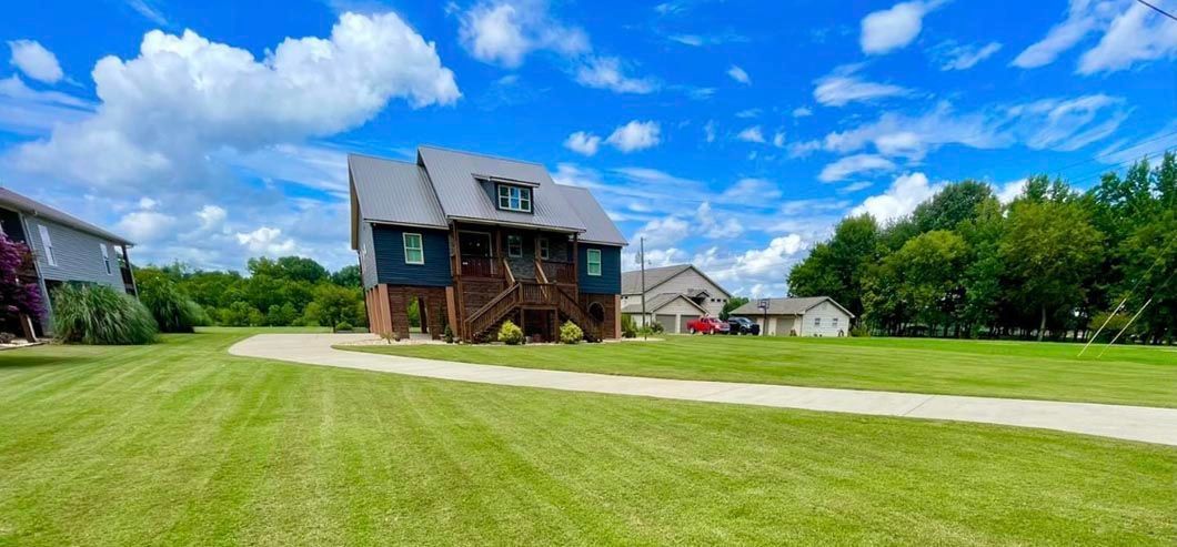 A large house is sitting in the middle of a lush green field.