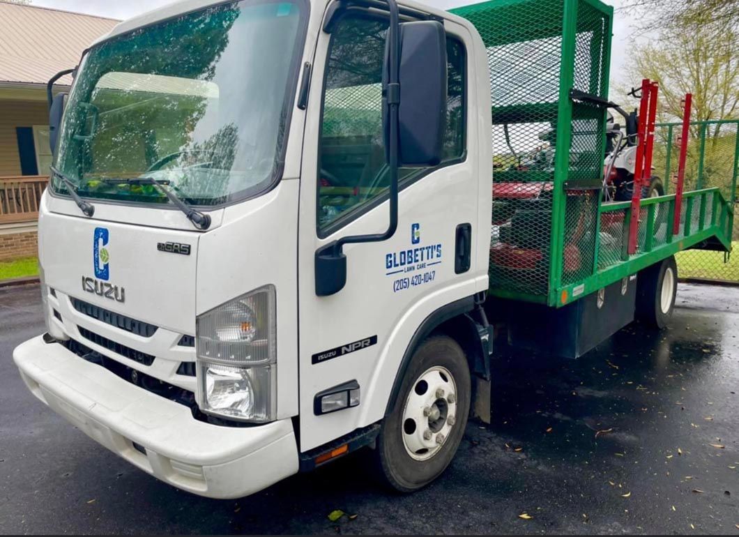 A white truck with a green trailer is parked in a driveway.
