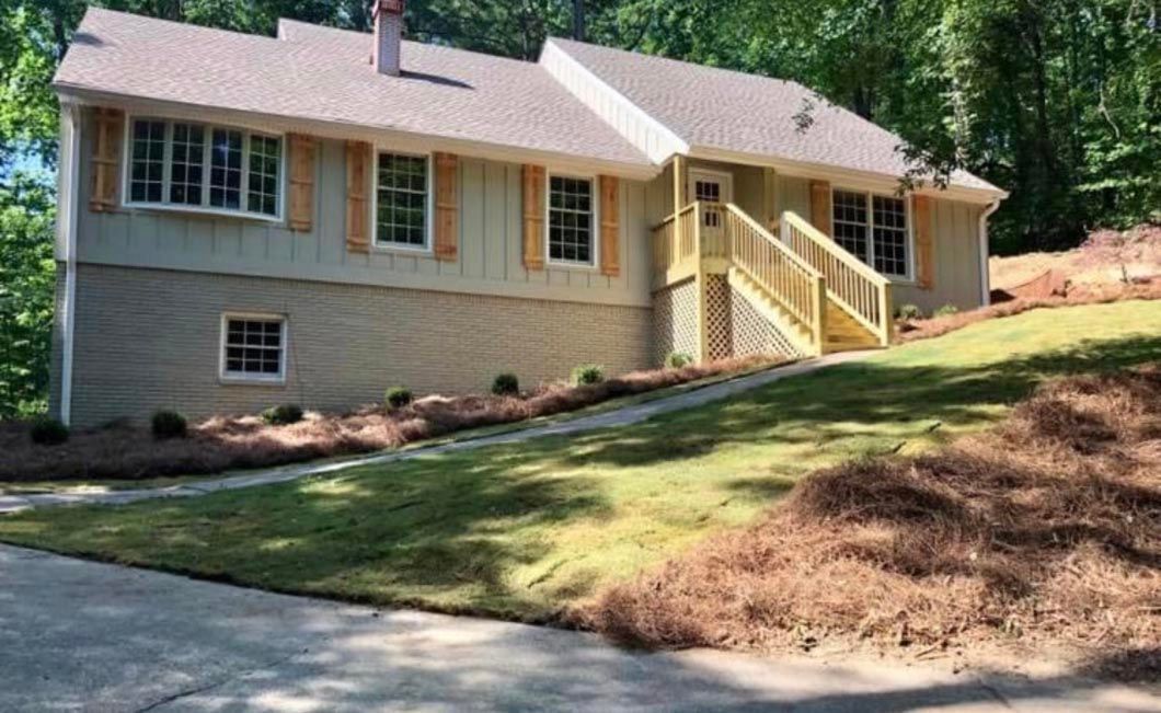 A house is sitting on top of a lush green hill surrounded by trees.