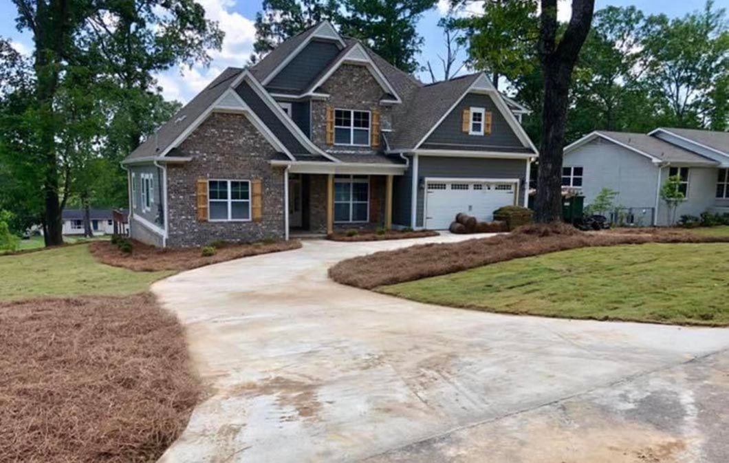 A large house with a driveway leading to it is surrounded by trees.