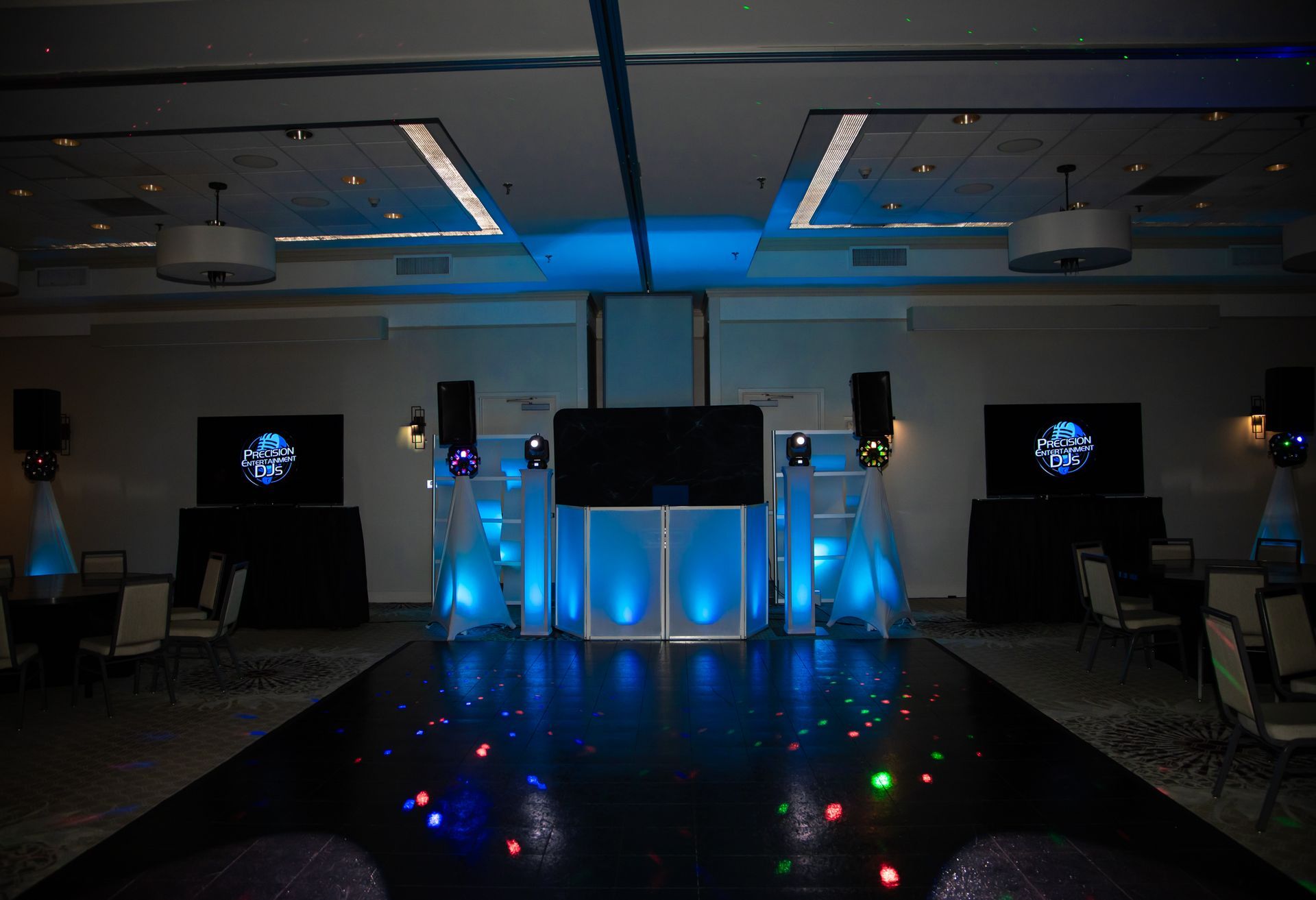 Stage setup with blue lighting, runway, and large screens.