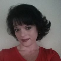 Woman with short, dark hair, red shirt, and dark lipstick smiles.