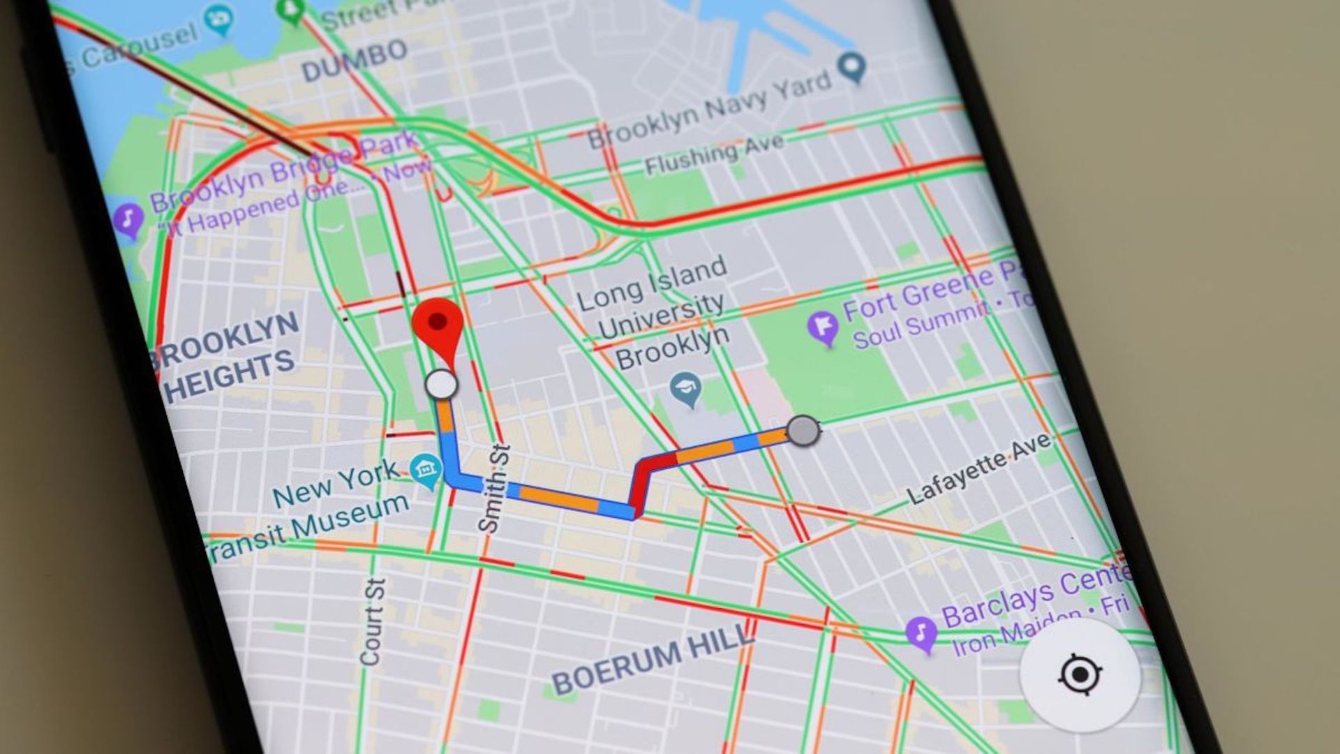 A smartphone screen displays a Google Maps navigation route in Brooklyn, with a red pin marking a destination.