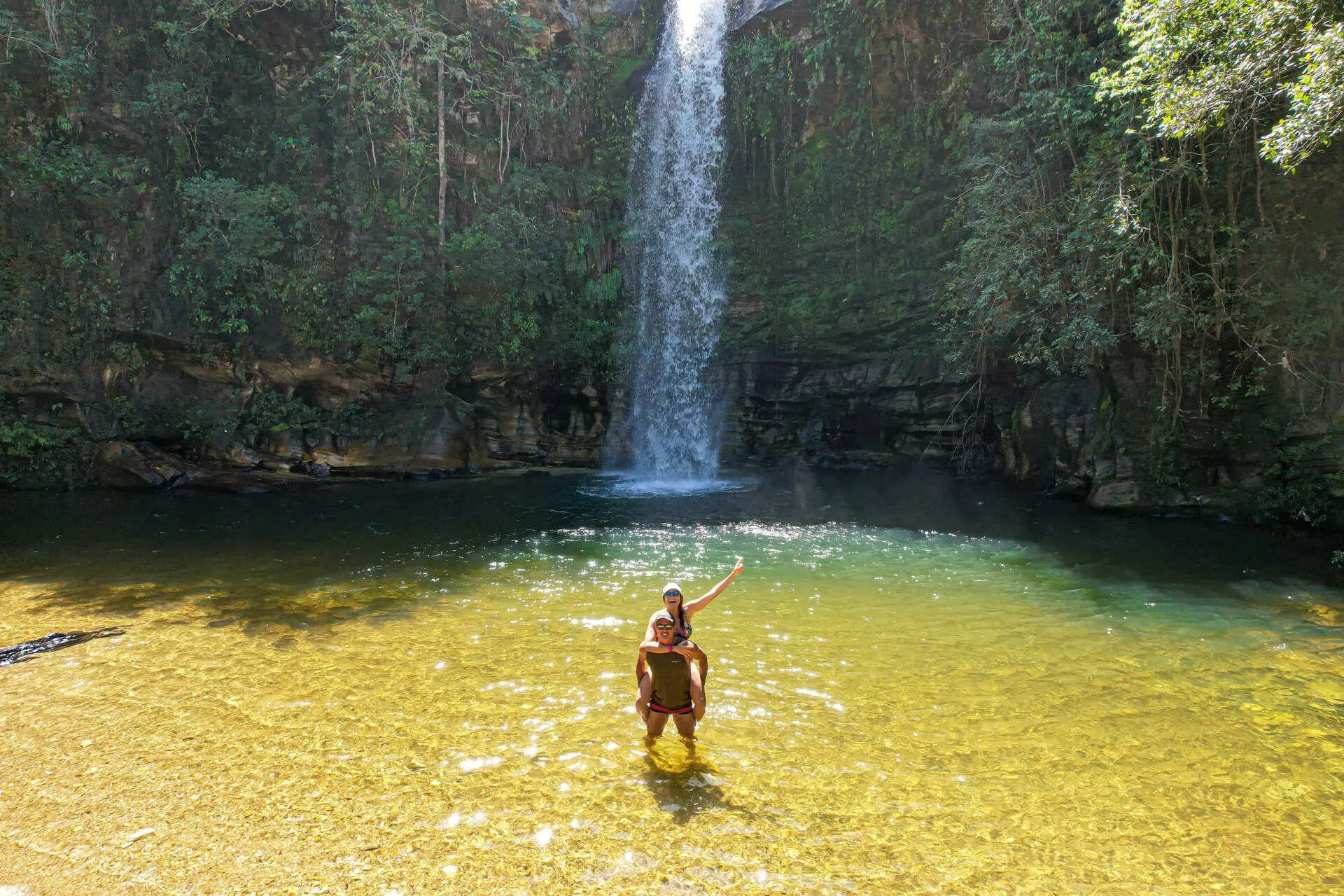 Um homem e uma mulher estão em frente a uma cachoeira - Pousada Flores do Cerrado