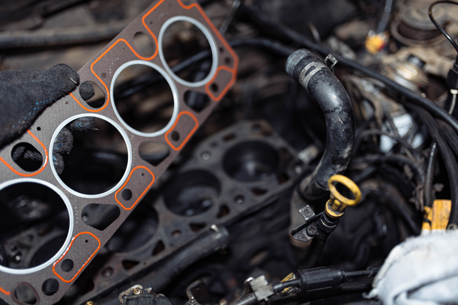 A close up of a person holding a head gasket on top of a car engine.