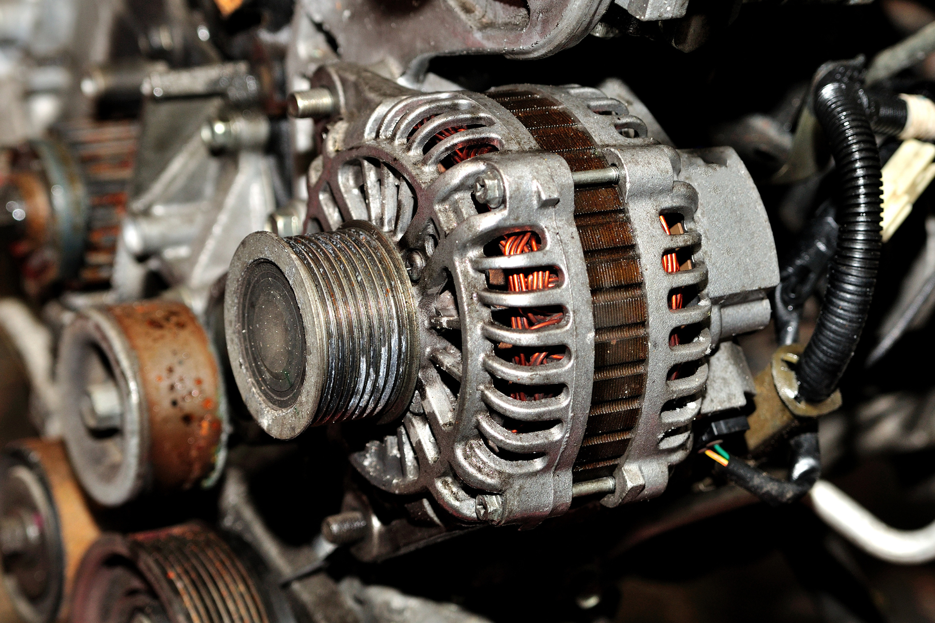 A close up of an alternator on top of a car engine.