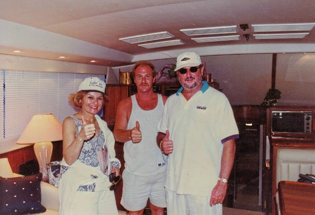 Two men and a woman are posing for a picture and the woman is giving a thumbs up