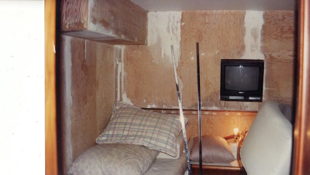 A small room with a bed and a television on the wall.