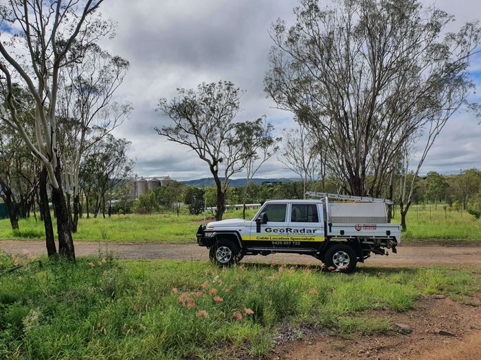 A white truck is parked on the side of a dirt road.