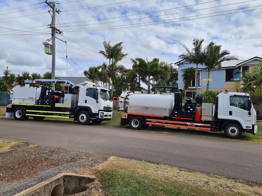 Two trucks are parked on the side of the road next to each other.