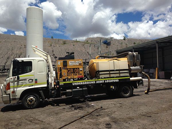 A vacuum truck is parked in front of a building.