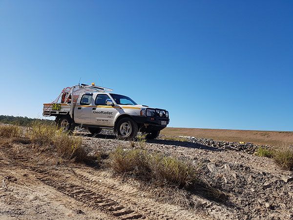 A truck is parked on the side of a dirt road.