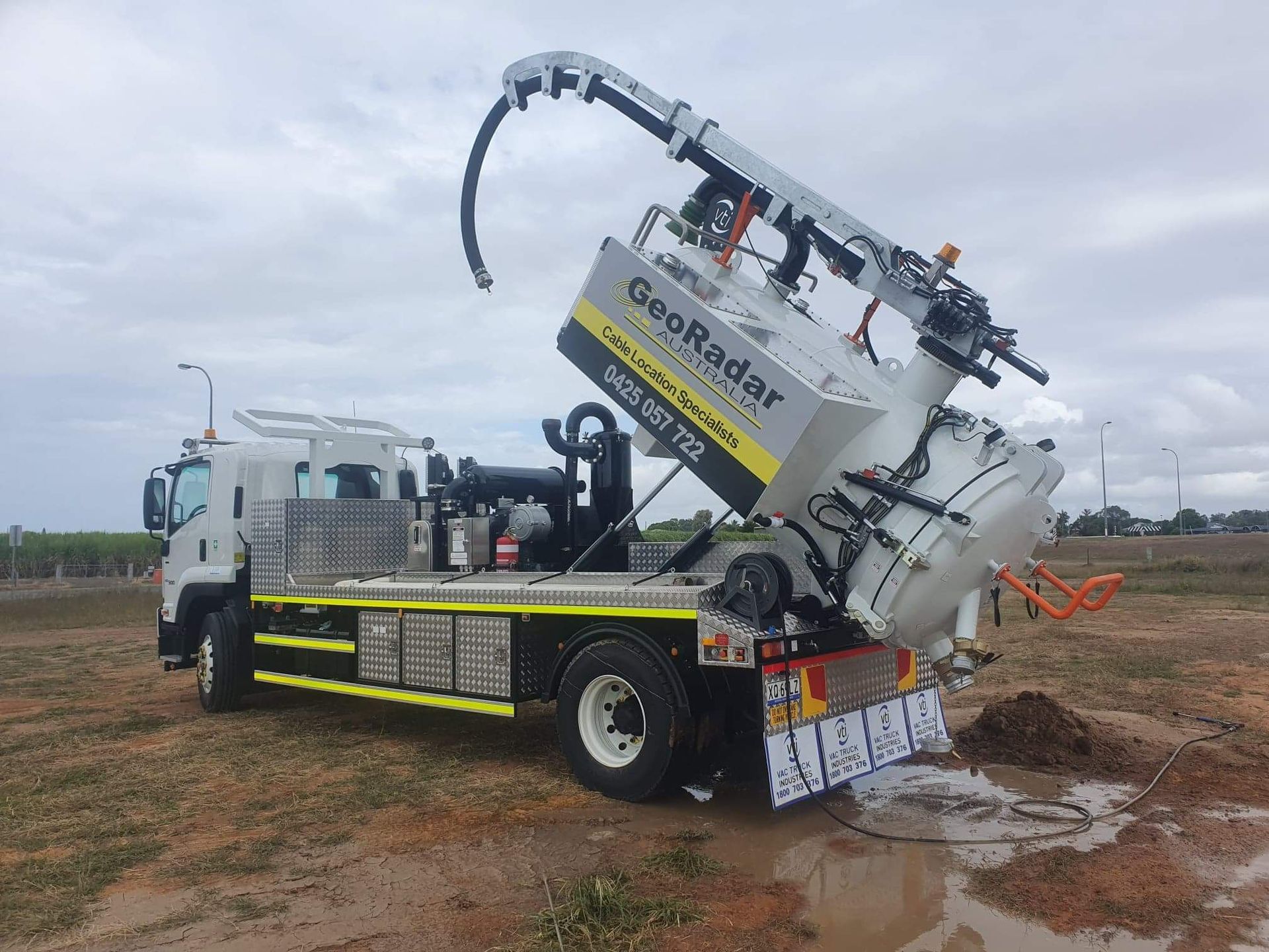 A vacuum truck is sitting in a muddy field.