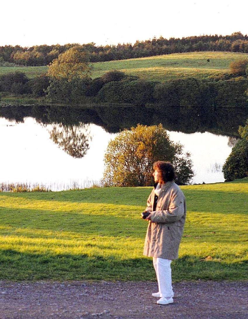 A woman standing in a field with a lake in the background