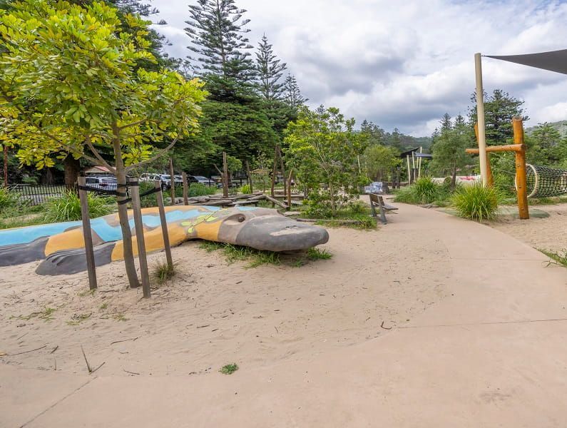 A playground with a snake shaped rock in the middle of it.