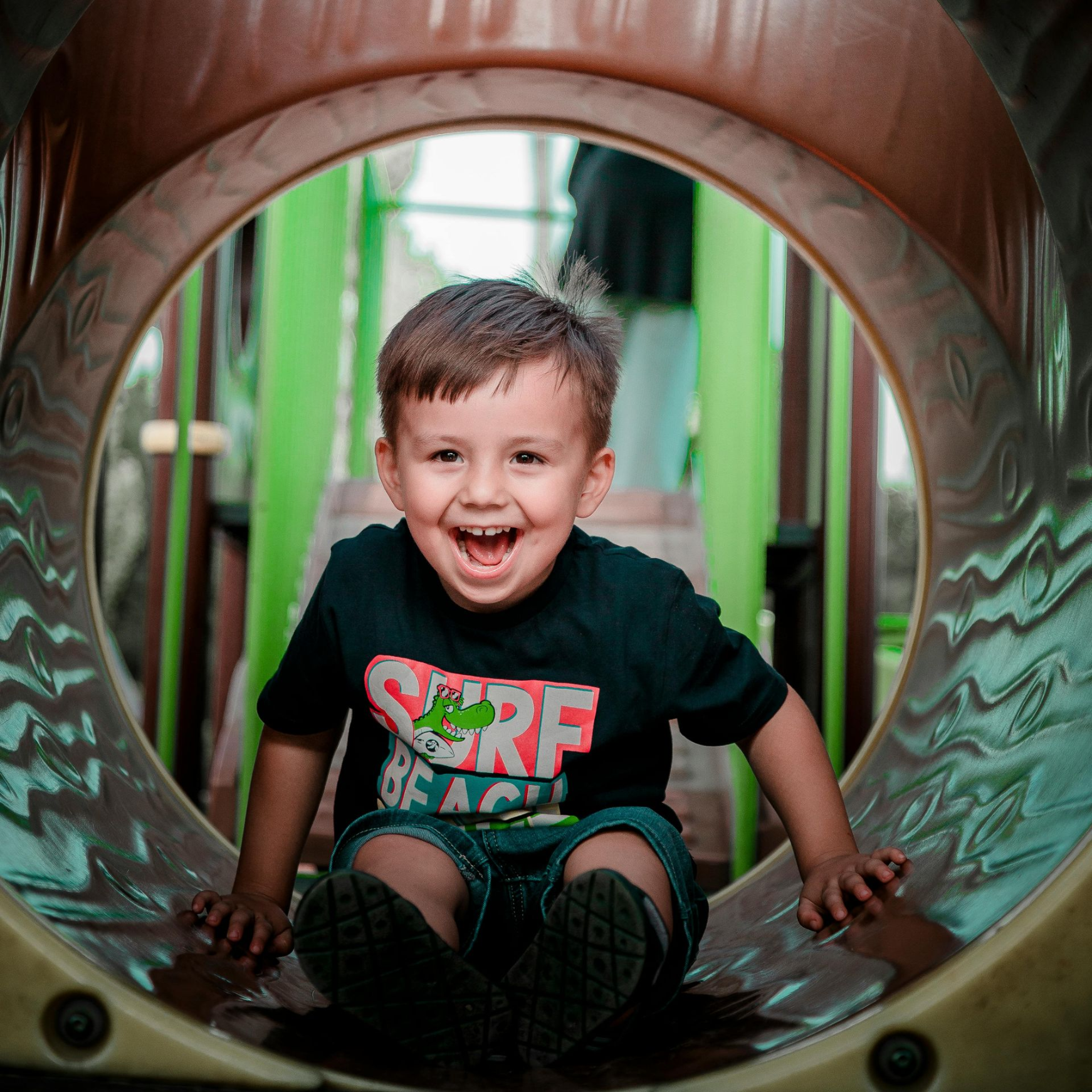 A playground with a snake shaped rock in the middle of it.