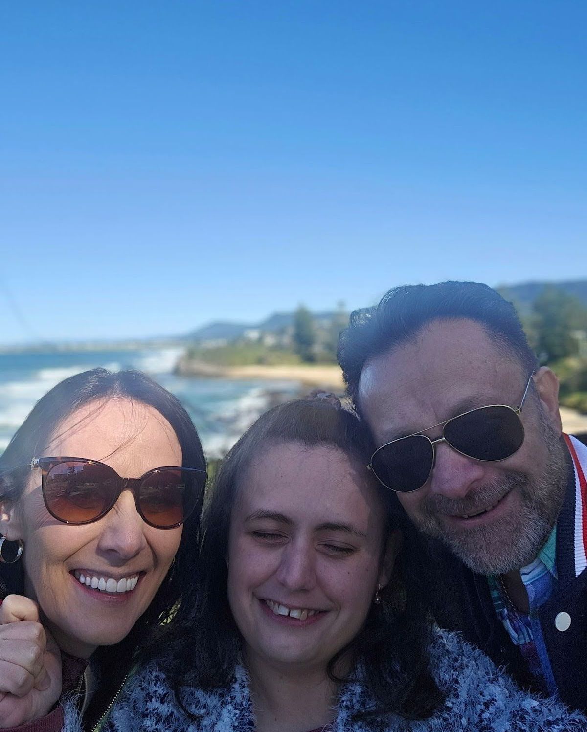 A man and two women are posing for a picture on the beach