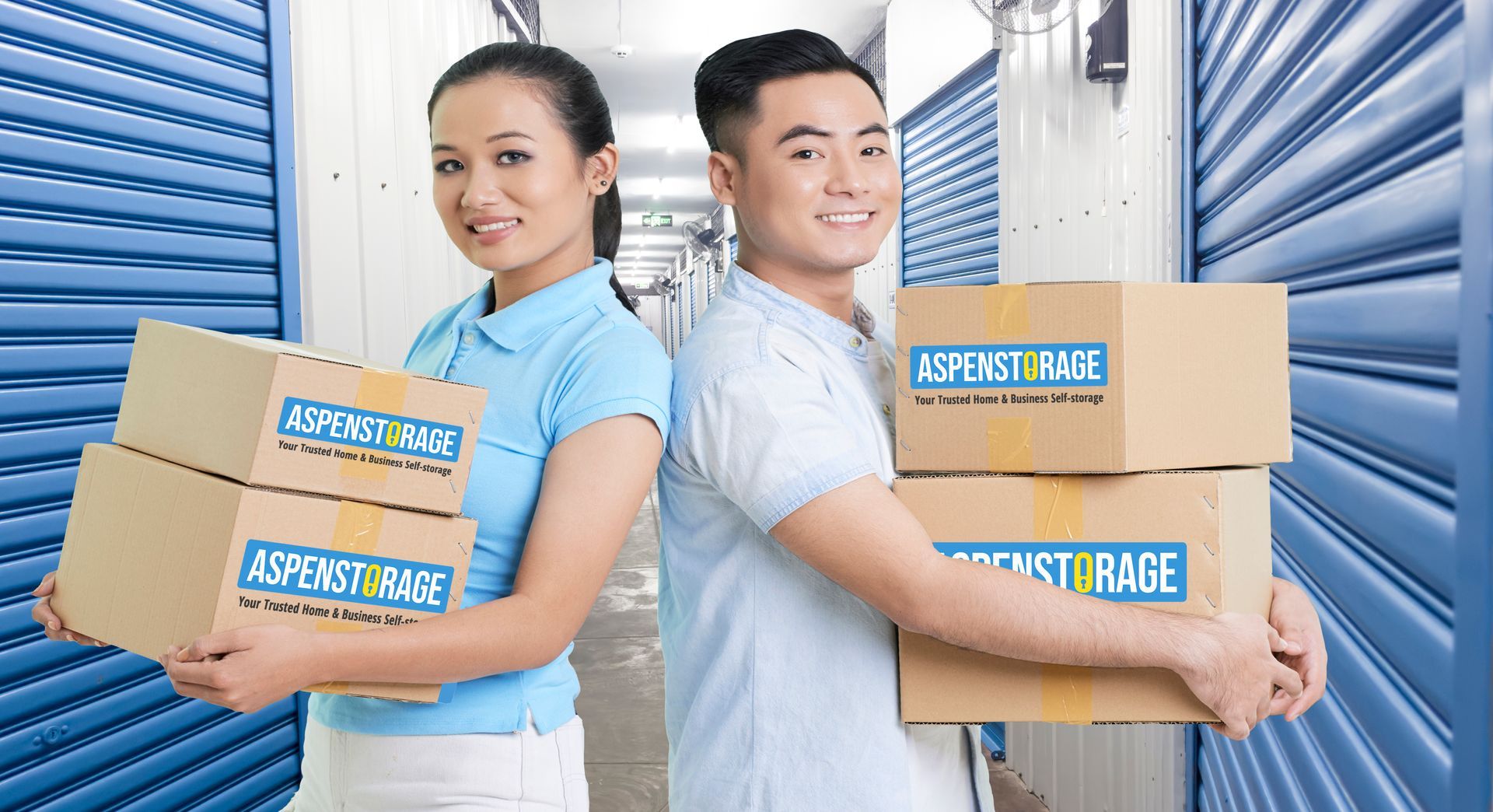 A man and a woman are standing back to back holding boxes.