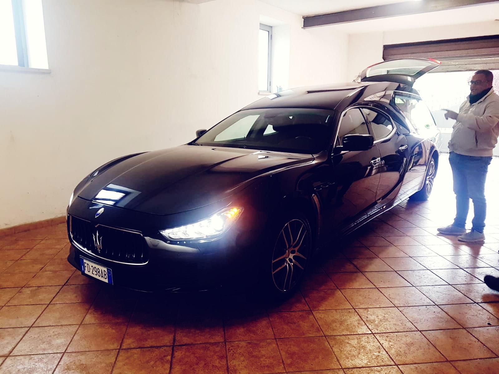 Un uomo è in piedi accanto a un'auto nera in un garage.