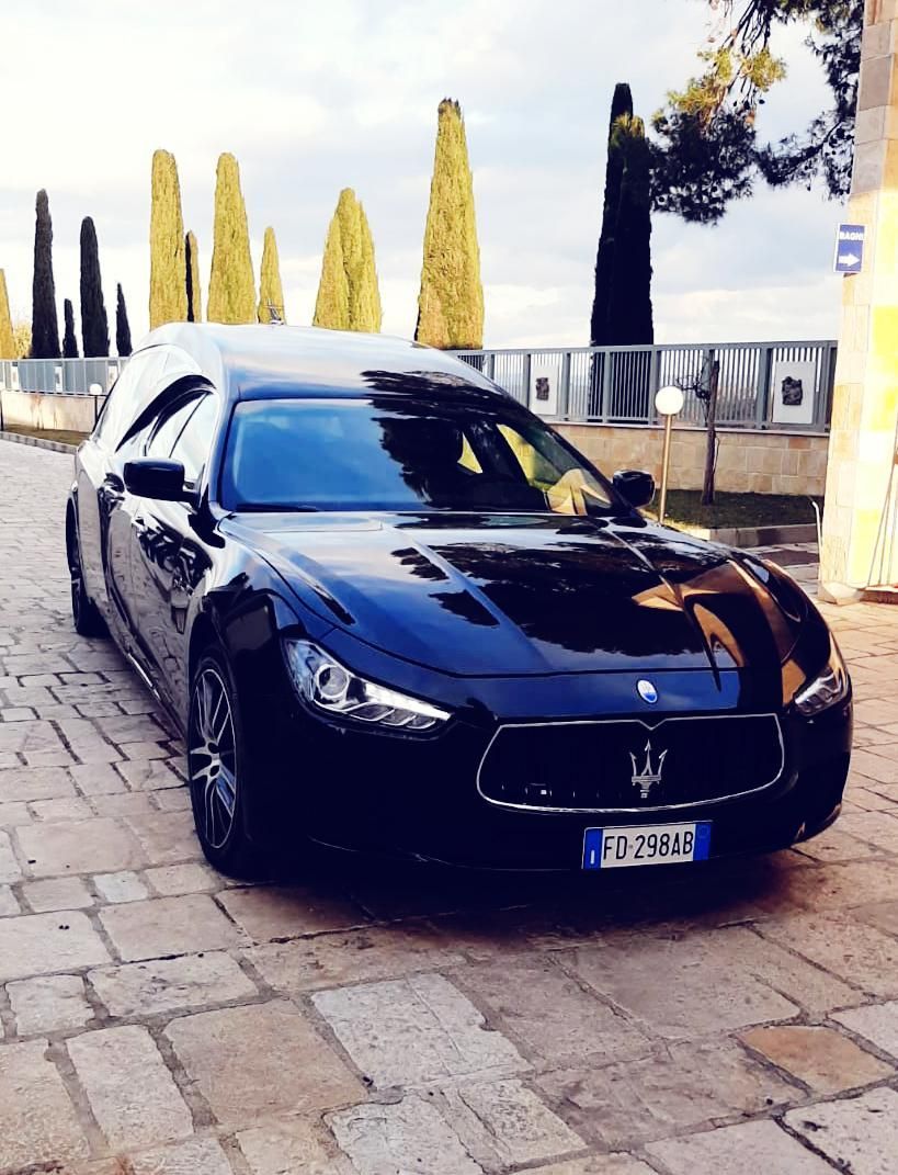 Una maserati nera è parcheggiata su una strada acciottolata.