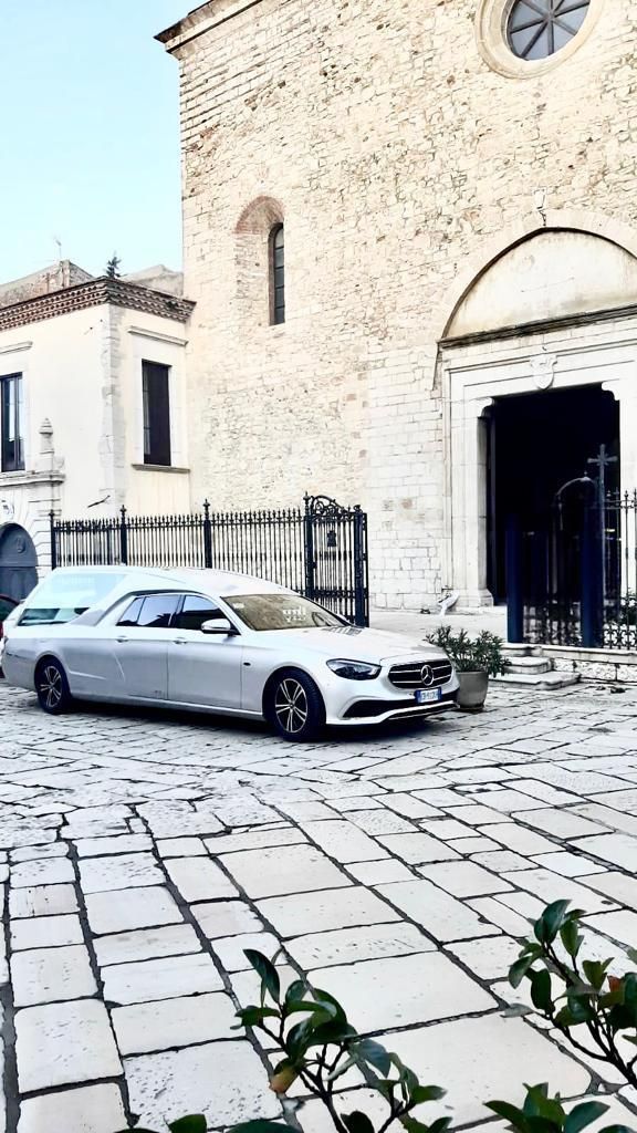 Un'auto bianca è parcheggiata davanti a un edificio in pietra.