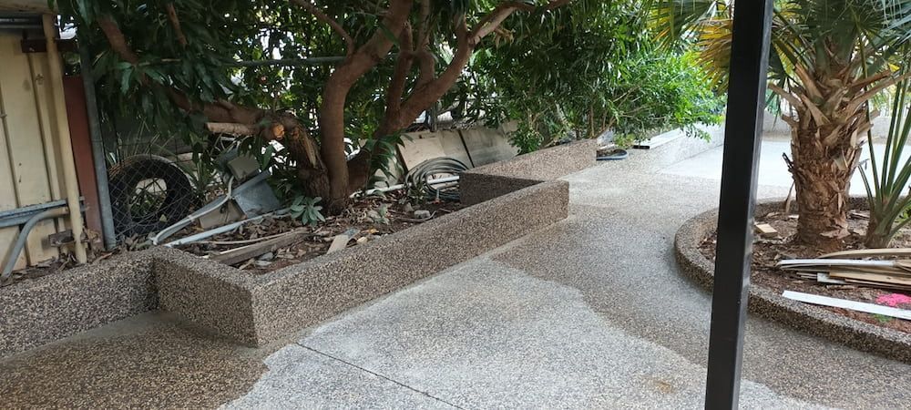 A Pebbled Walkway Curves Past a Tree and Planter — KNG Roofing And Construction in Darwin, NT