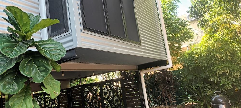 A Modern House With a Green Plant in the Foreground — KNG Roofing And Construction in Darwin, NT
