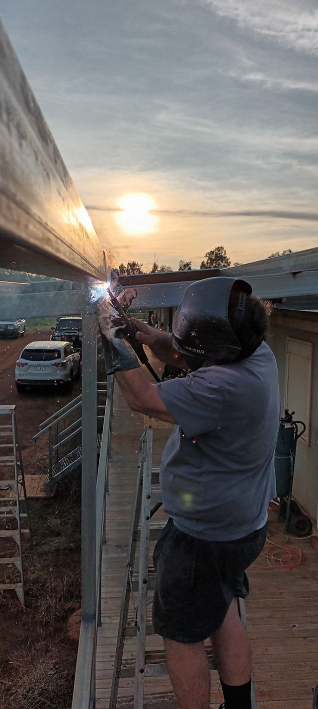 A Person Welding Metal in Front of the Sunset — KNG Roofing And Construction in Darwin, NT