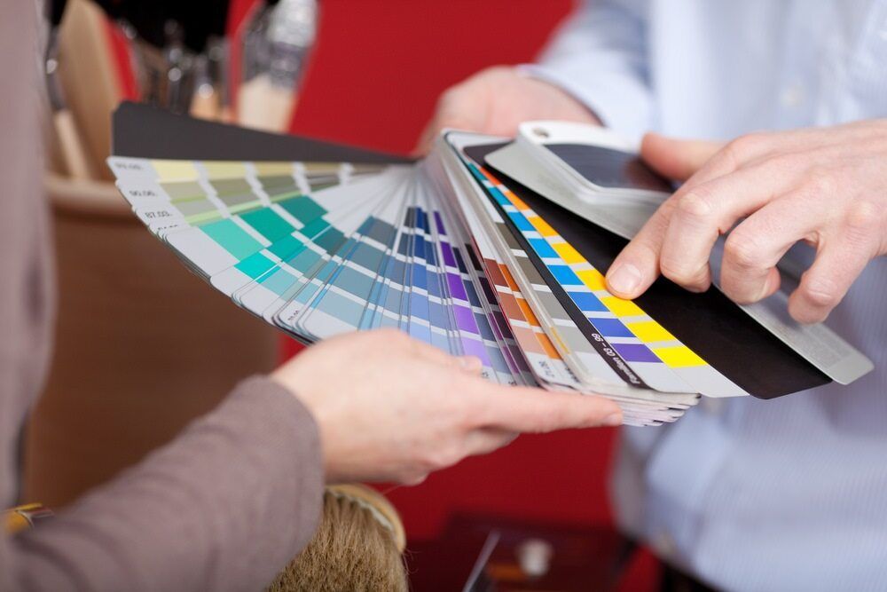 Two People Choosing Paint Colours From a Colour Swatch Fan — KNG Roofing And Construction in Gove, NT