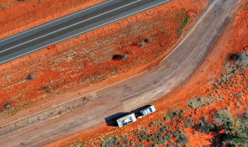 Aerial View of a Truck and Trailer on a Red Dirt Road Curving — KNG Roofing And Construction in Tennant Creek, NT