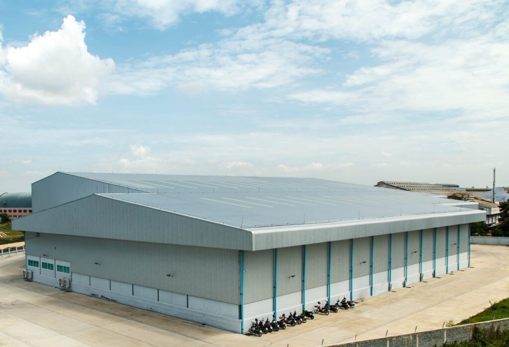 Warehouse Building Under a Blue Sky, With a Grey Roof and Light Blue Walls — KNG Roofing And Construction in Gove, NT