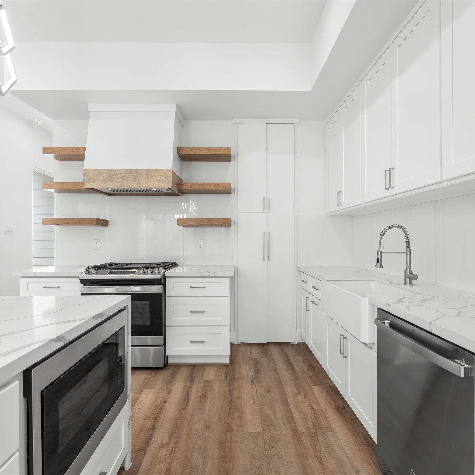 White kitchen with wooden shelves and stainless steel appliances.