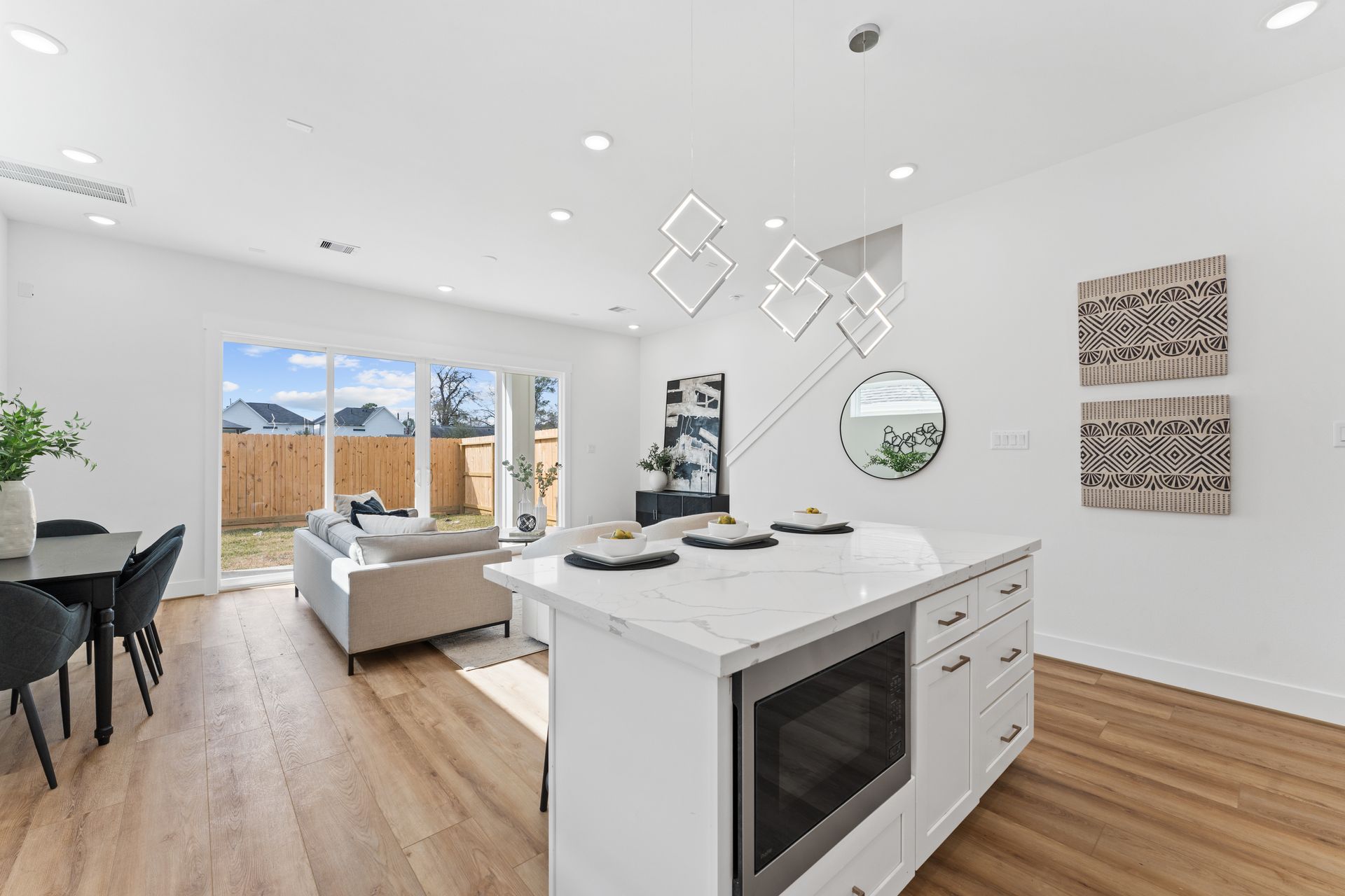 Open-concept kitchen with white island, a dining area, and a living room with a view of the backyard.