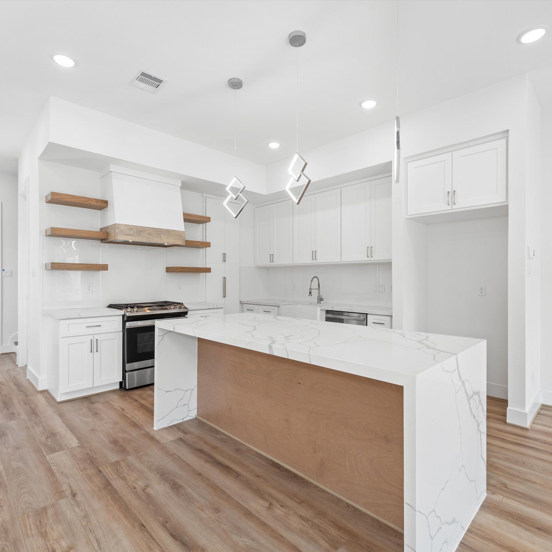 Modern white kitchen with wooden accents; island with marble countertop; wood floors.