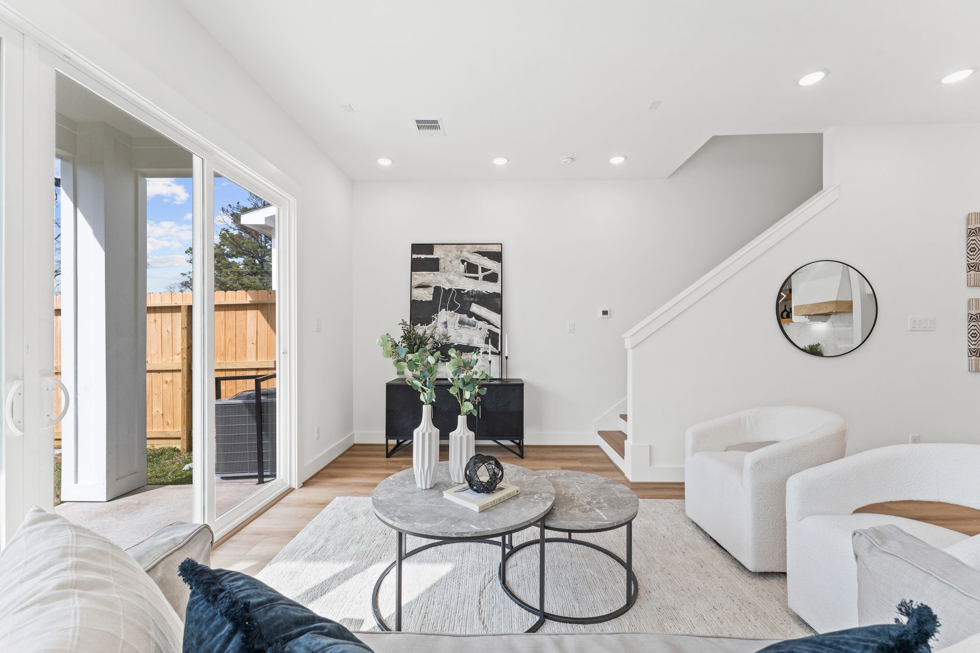 Bright living room with white walls, two white armchairs, and a coffee table.