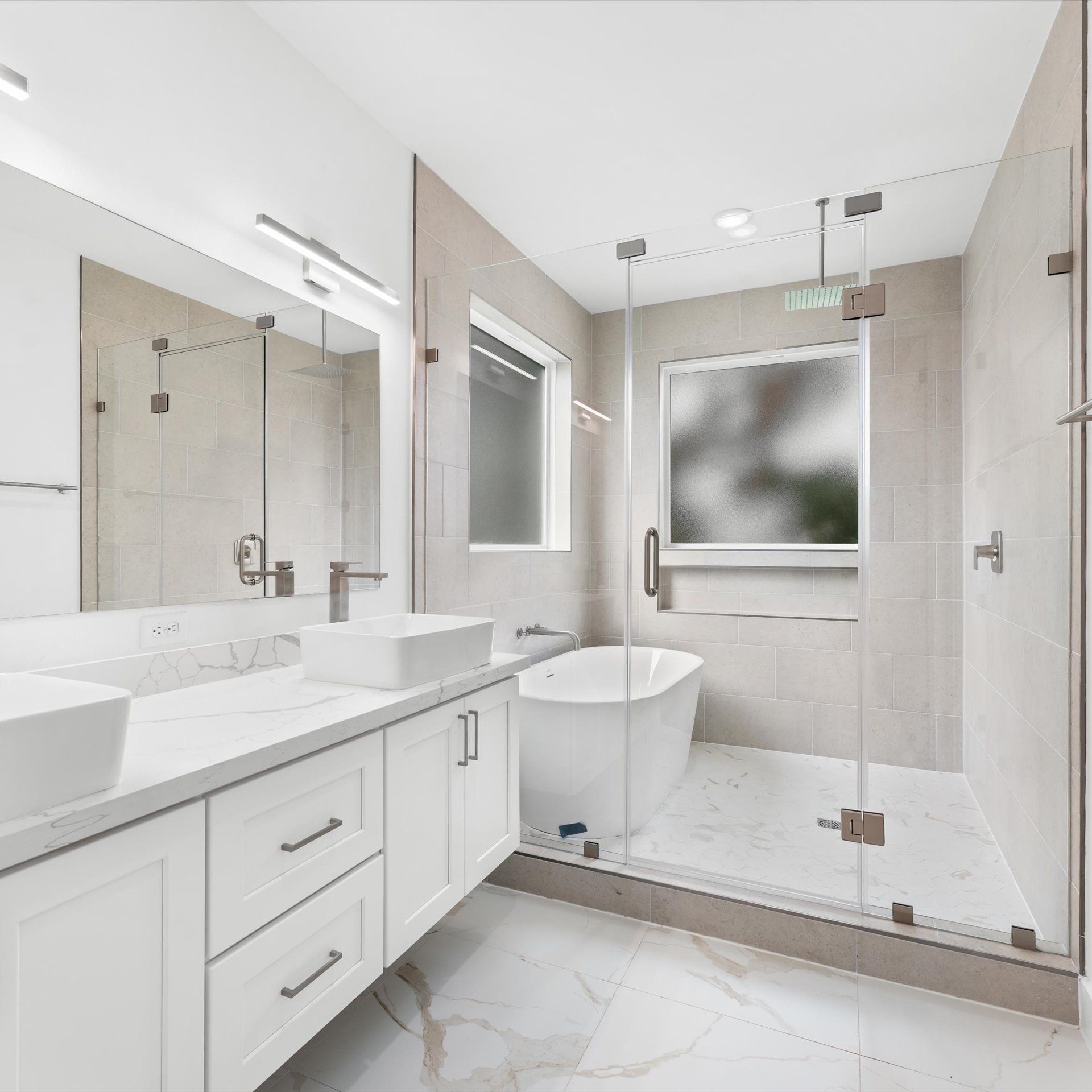 Modern, white bathroom with dual sinks, a tub, and a glass shower. Soft, neutral colors.