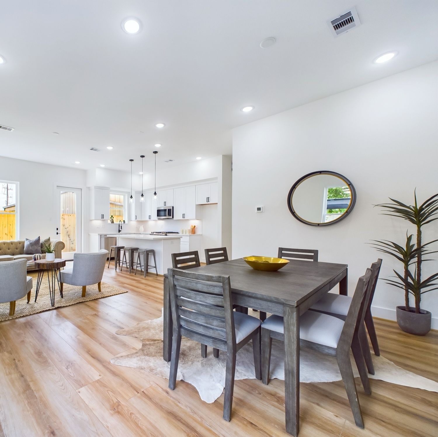 Dining room with gray table and chairs, wood floors, and open concept to kitchen.