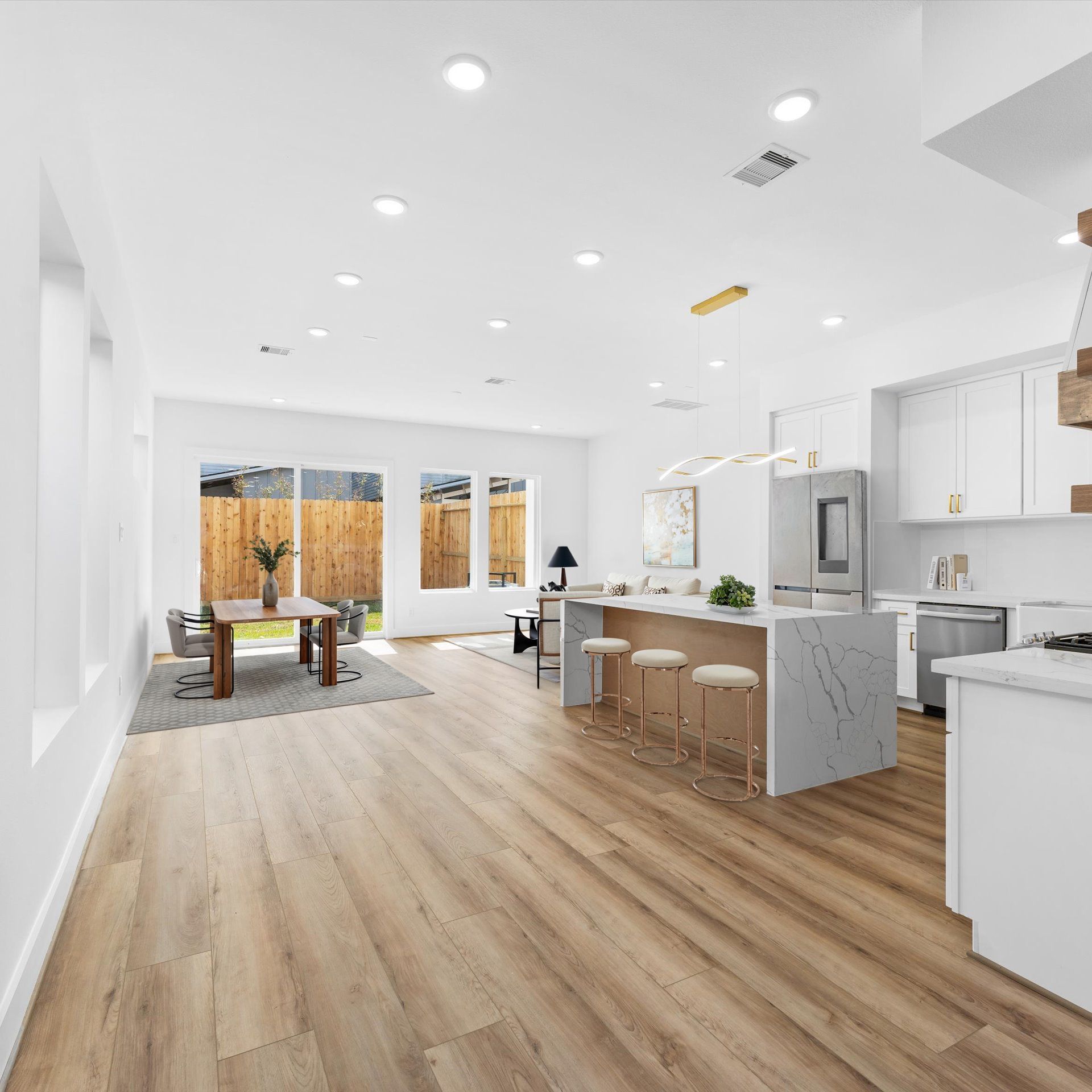 Modern kitchen and dining area with white cabinets, wooden floors, and a kitchen island with seating.