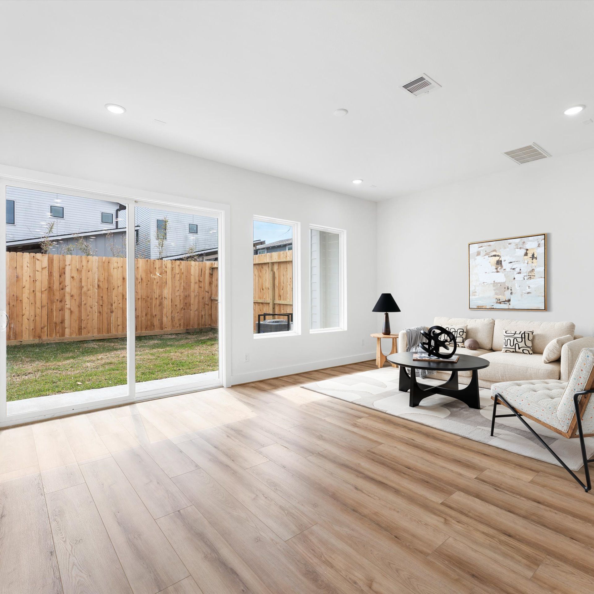 Living room with sliding glass door to backyard, wood floors, and modern furniture.