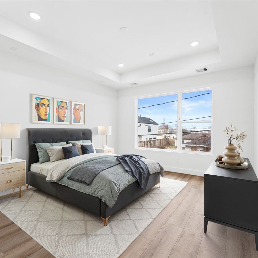 Bedroom with bed, nightstands, art, and large window. Light wood floors, gray and white color scheme.