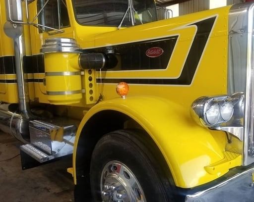 Yellow Peterbilt semi-truck with black accents, chrome details, and amber lights.