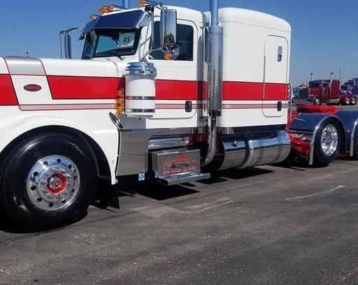 White semi-truck with red stripes parked on asphalt under a blue sky, chrome details.