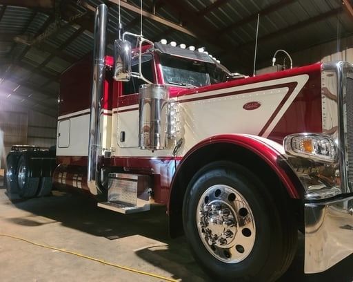 Red and white Peterbilt semi-truck parked inside a garage.