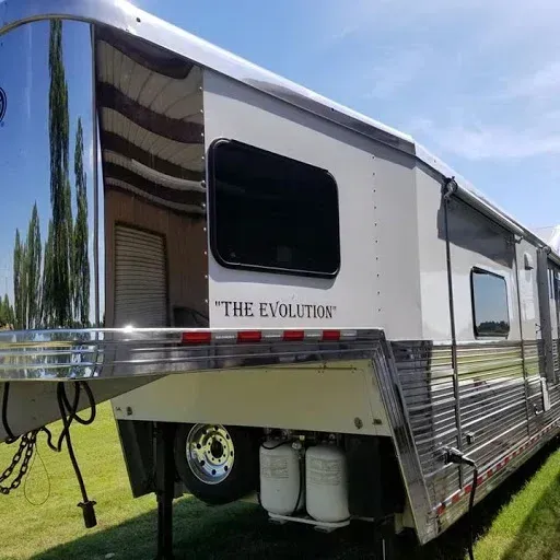 Horse trailer, silver and white with chrome accents, parked on grass; 
