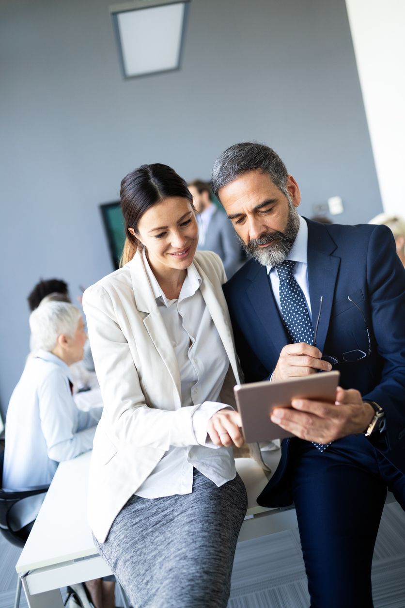 a man and a woman looking at a tablet in an office