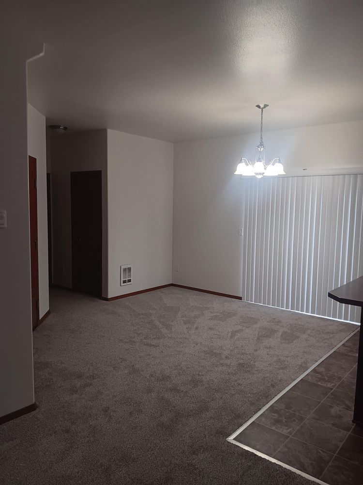 Empty living room with white walls and a window with blinds.