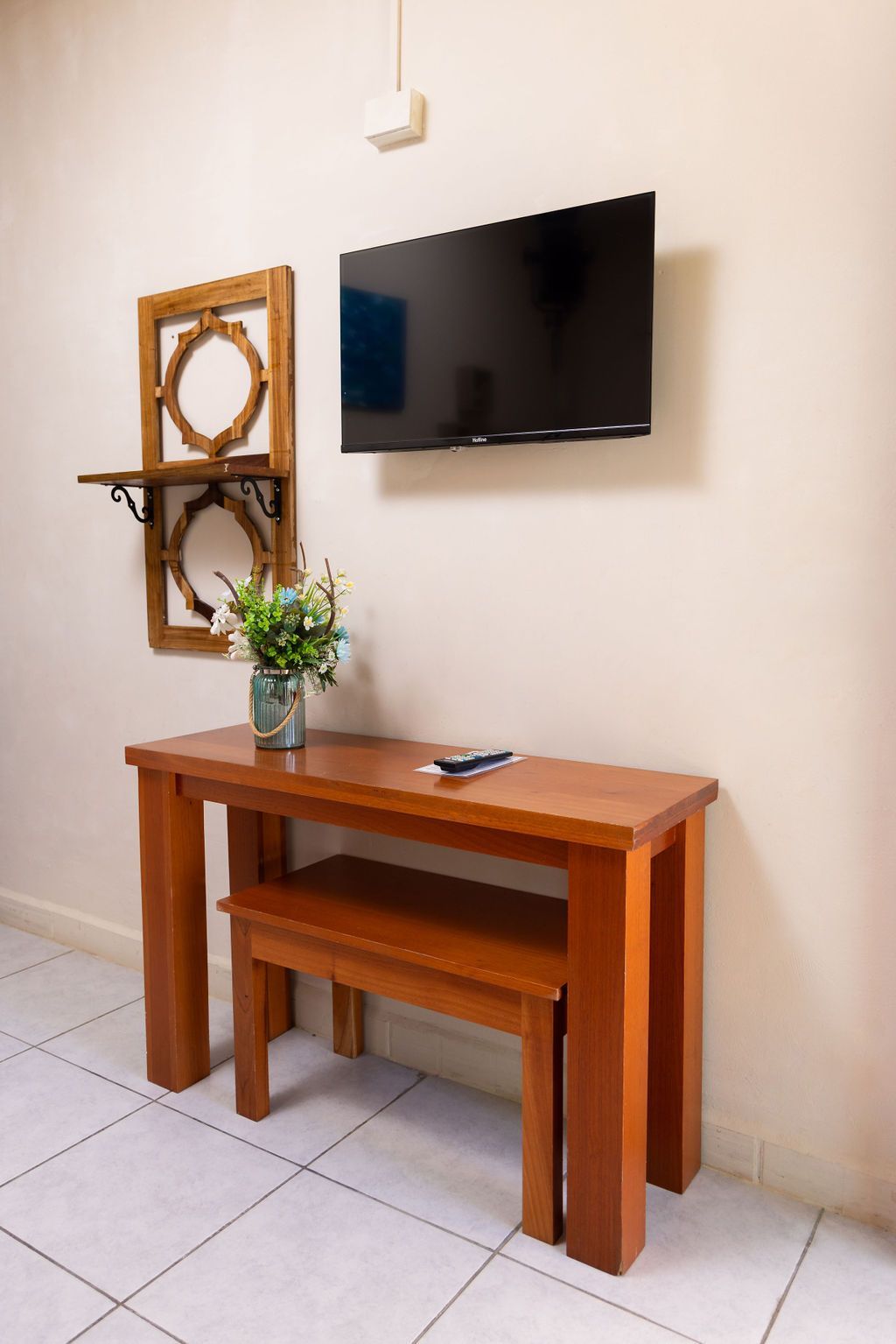 Conjunto de mesa y banco de madera con TV y estante sobre pared blanca.