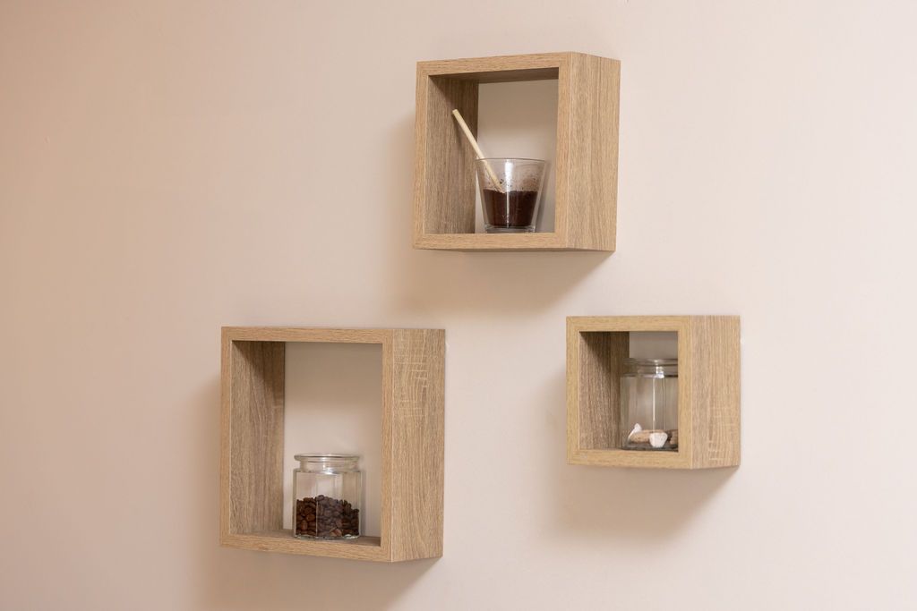 Tres estantes de pared cuadrados de madera, cada uno con un vaso o frasco pequeño, montados en una pared neutra.
